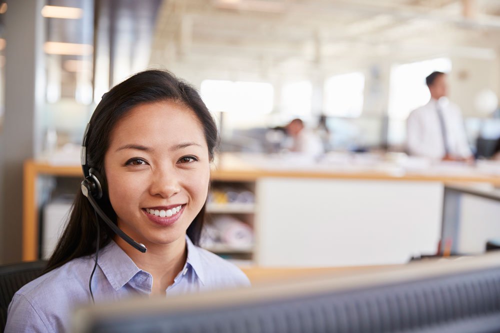 young asian woman working in a call centre smiling