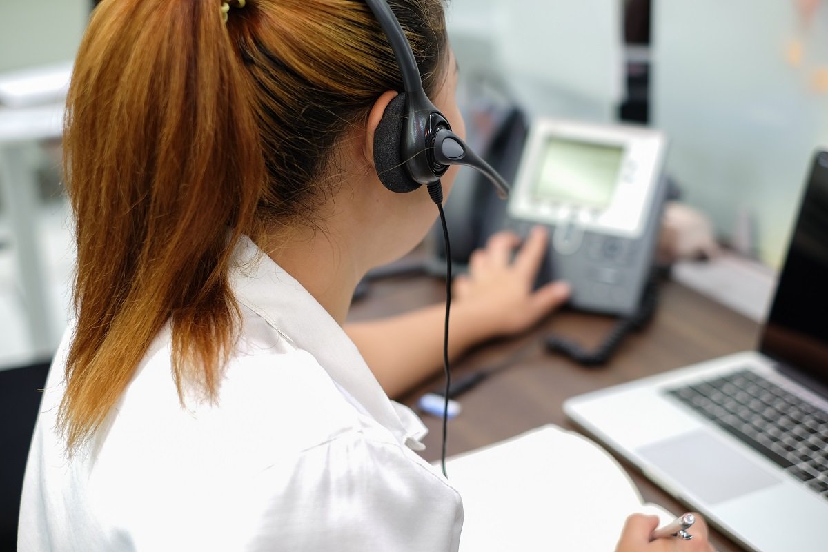 woman wearing a headset dialing on the phone