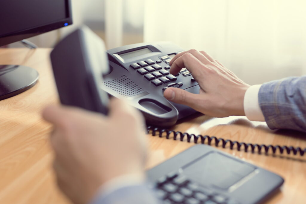 a professional man dialing voip phone in the office