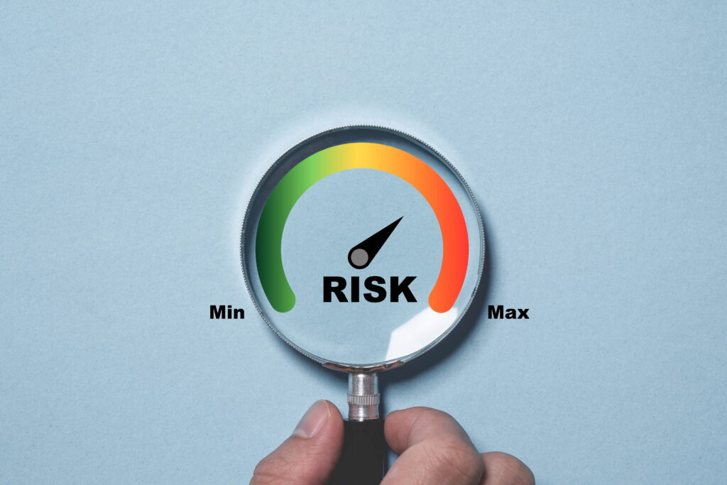 Magnifying glass focused on a risk level gauge with a needle indicating moderate-to-high risk