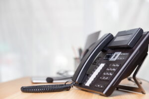Business IP phone with handset, keypad, and display on an office desk