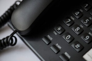 Close-up of a black office desk phone keypad showing tone, pause, flash, and redial buttons